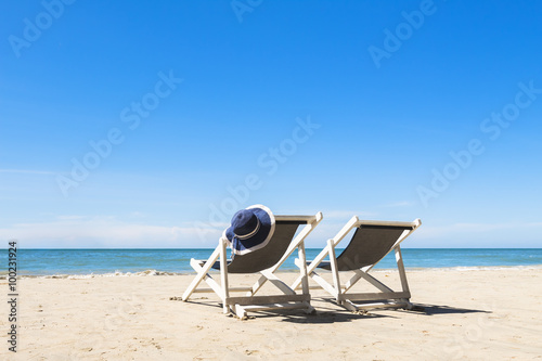 Two deck chairs and hat, relaxing on the beach, sunny photo