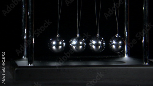 Newton's Cradle balls colliding on black background.