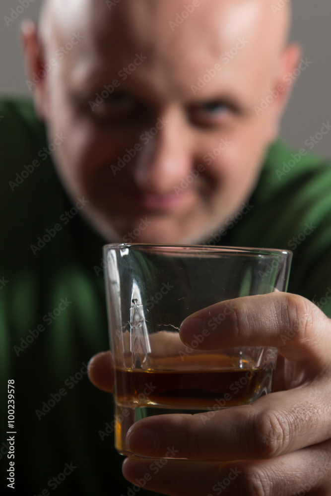 Bald headed man drinking whiskey