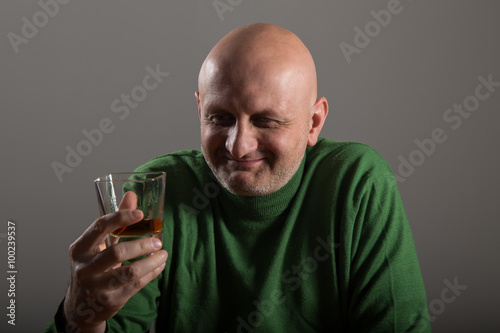Bald headed man drinking whiskey