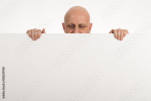 Bald man peeps over top of blank white paper