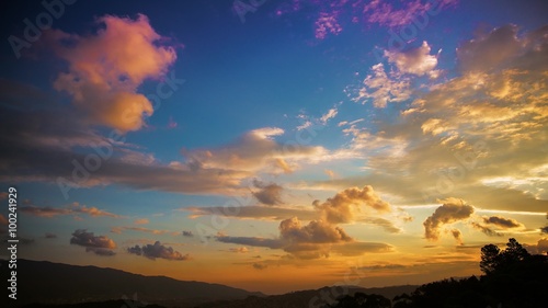 Very colorful day to night time lapse of clouds at sunset in the tropic. The sun flashes all around during the setting and city lights showoff at night