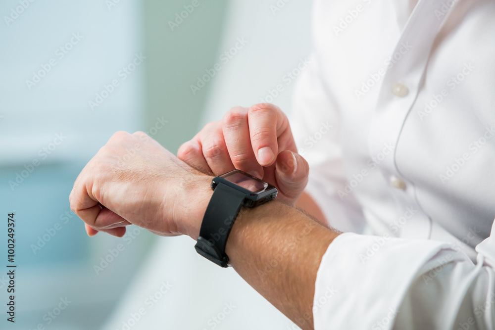 Man in white shirt using his smart watch. Close-up hands on interior background