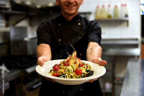 Happy chef holding delicious pasta