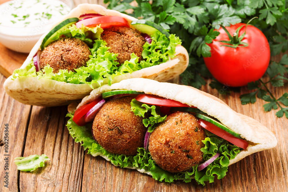 Falafel and fresh vegetables in pita bread on wooden table Falafel and fresh vegetables in pita bread on wooden table