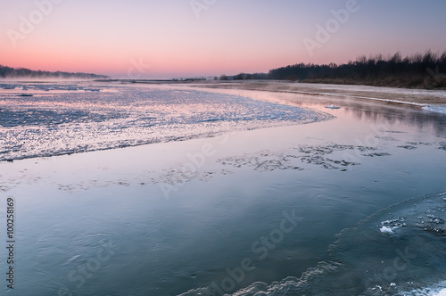 Freezing river covered in fog during dusk