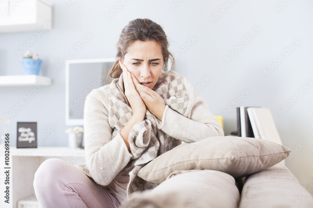 Portrait of young woman sitting in the living room with hard toothache,shallow depth of field Portrait of young woman sitting in the living room with hard toothache,shallow depth of field