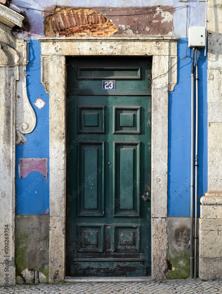 Naklejka premium Antique abandoned building facade with green wood door