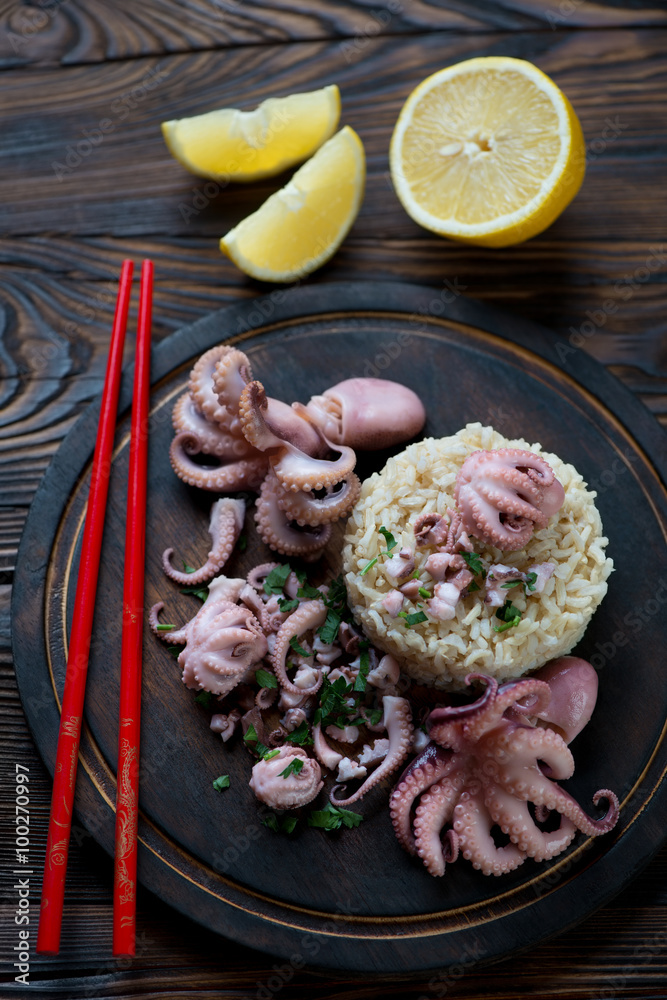 Top view of octopuses with brown rice on a rustic chopping board