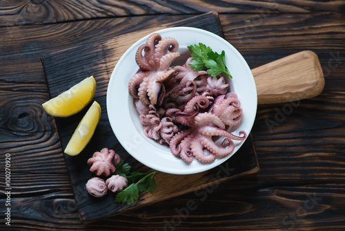 Baby octopuses with lemon and parsley on a rustic wooden surface