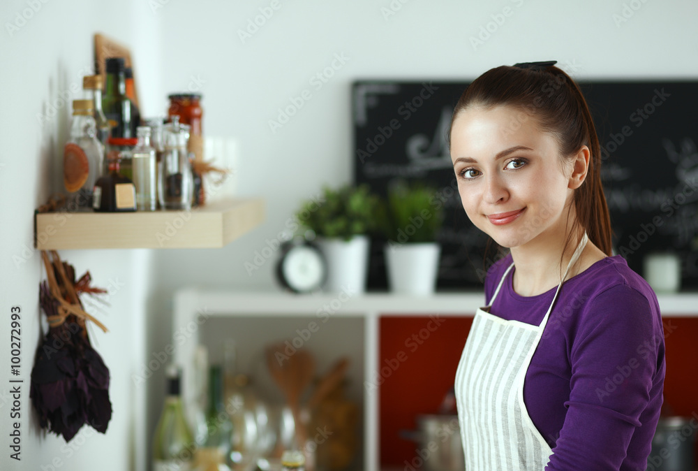 Young woman standing in her kitchen near desk with shopping bags Young woman standing in her kitchen near desk with shopping bags