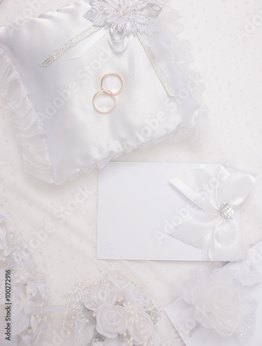 The wedding invitation with wedding rings and a bouquet of the bride on a white background