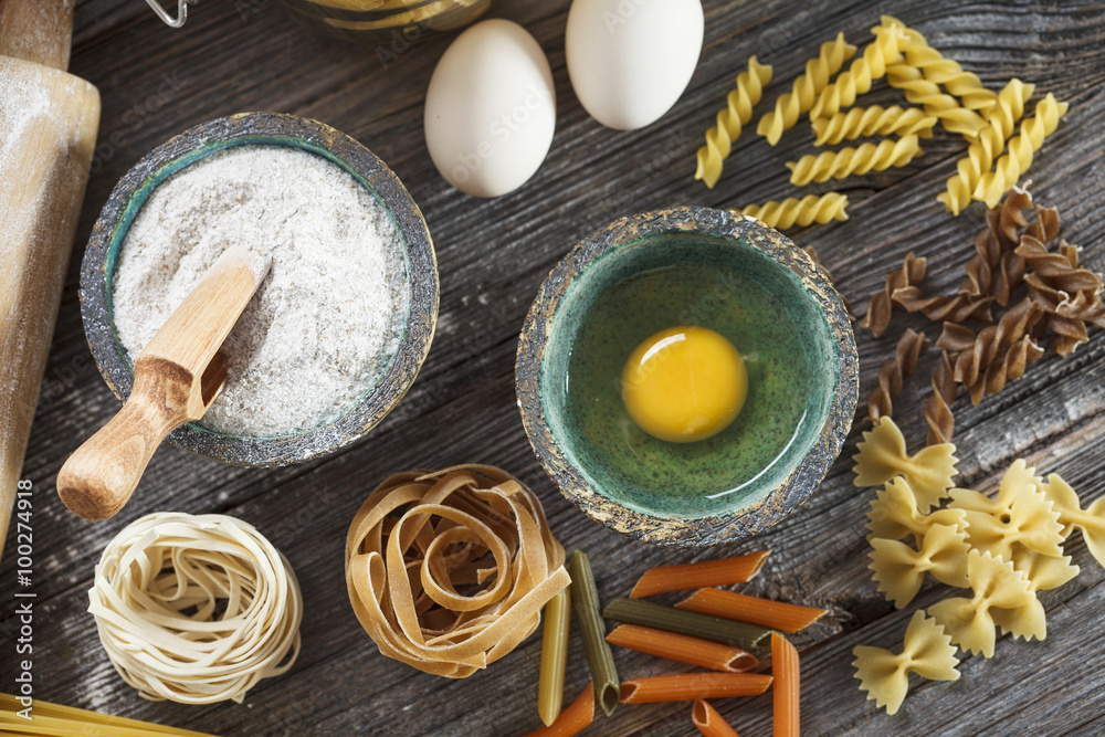 A set of raw pasta and addons on wooden table A set of raw pasta and addons on wooden table