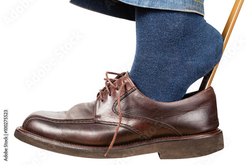 man puts on brown shoes using shoe horn isolated photo