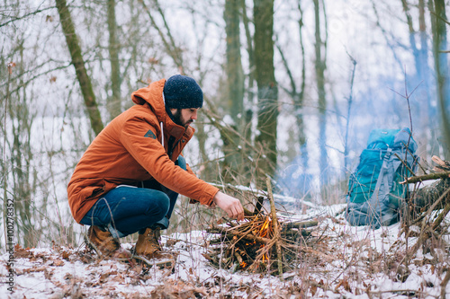 Hiker makes a fire in the winter woods