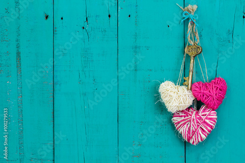 Pink and white hearts and key hanging on teal blue wood door