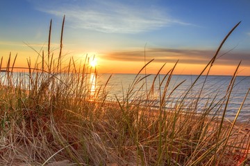 Dawn Of A New Day.Beautiful sunrise illuminates  sand dunes and the blue water horizon as a new day begins. Port Austin, Michigan.