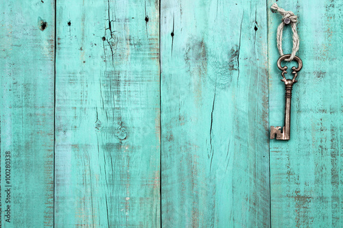 Bronze skeleton key hanging by rope on blank antique mint green rustic wood door