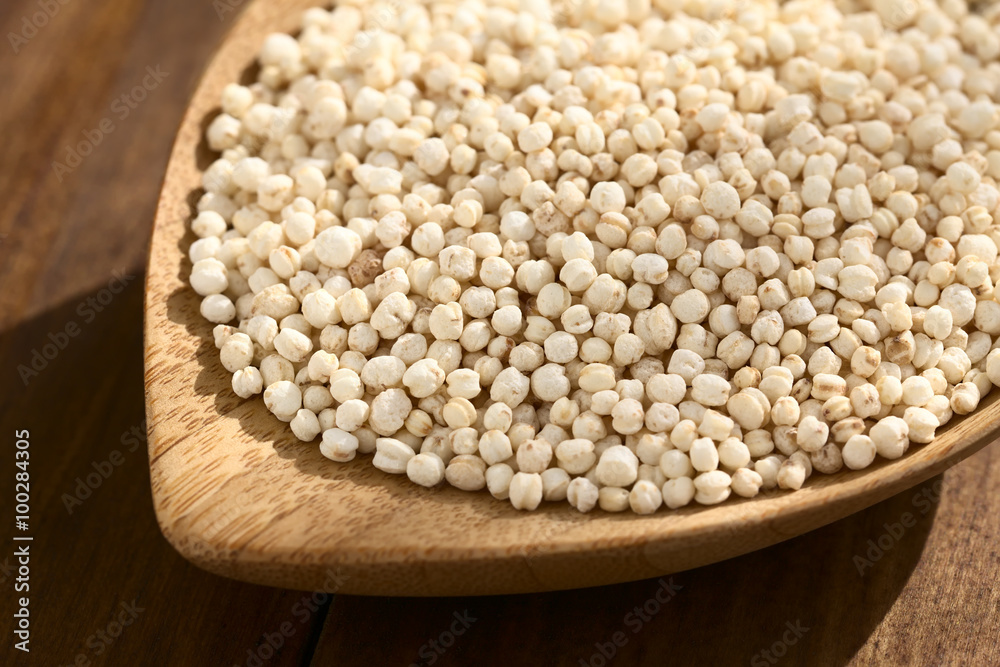Popped white quinoa (lat. Chenopodium quinoa) cereal on small wooden plate, photographed on wood with natural light (Selective Focus, Focus one third into the quinoa cereal) Popped white quinoa (lat. Chenopodium quinoa) cereal on small wooden plate, photographed on wood with natural light (Selective Focus, Focus one third into the quinoa cereal)