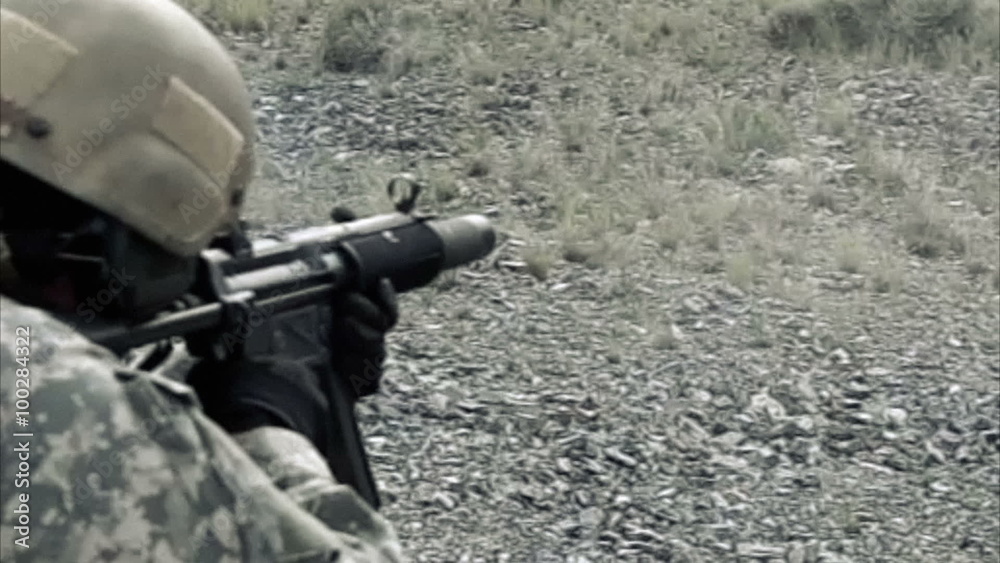 Static shot, soldier shooting automatic small target rifle at range while kneeling. Static shot, soldier shooting automatic small target rifle at range while kneeling.