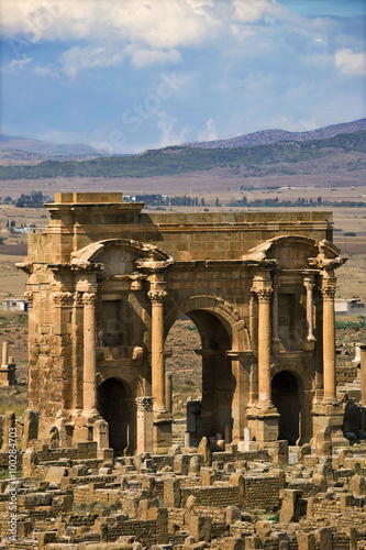 Algeria. Timgad (ancient Thamugadi or Thamugas). Triumphal arch, called Trajan's Arch (Corinthian order with three arches) viewed from scene of theatre