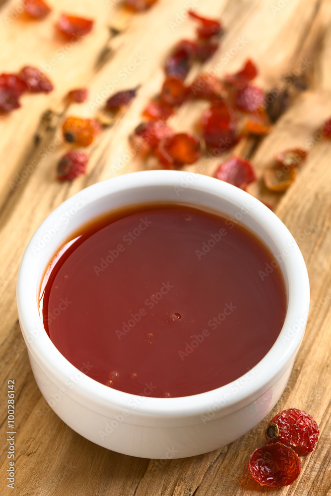Homemade rose hip jam in bowl with dried rosehip on the side, photographed on wood with natural light (Selective Focus, Focus on the middle of the jam) Homemade rose hip jam in bowl with dried rosehip on the side, photographed on wood with natural light (Selective Focus, Focus on the middle of the jam)