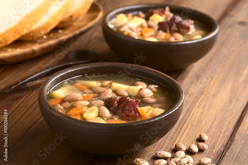 Traditional Hungarian Babgulyas bean goulash soup made of pinto beans, smoked meat, potato, carrot, csipetke (homemade soup pasta), photographed with natural light (Selective Focus)