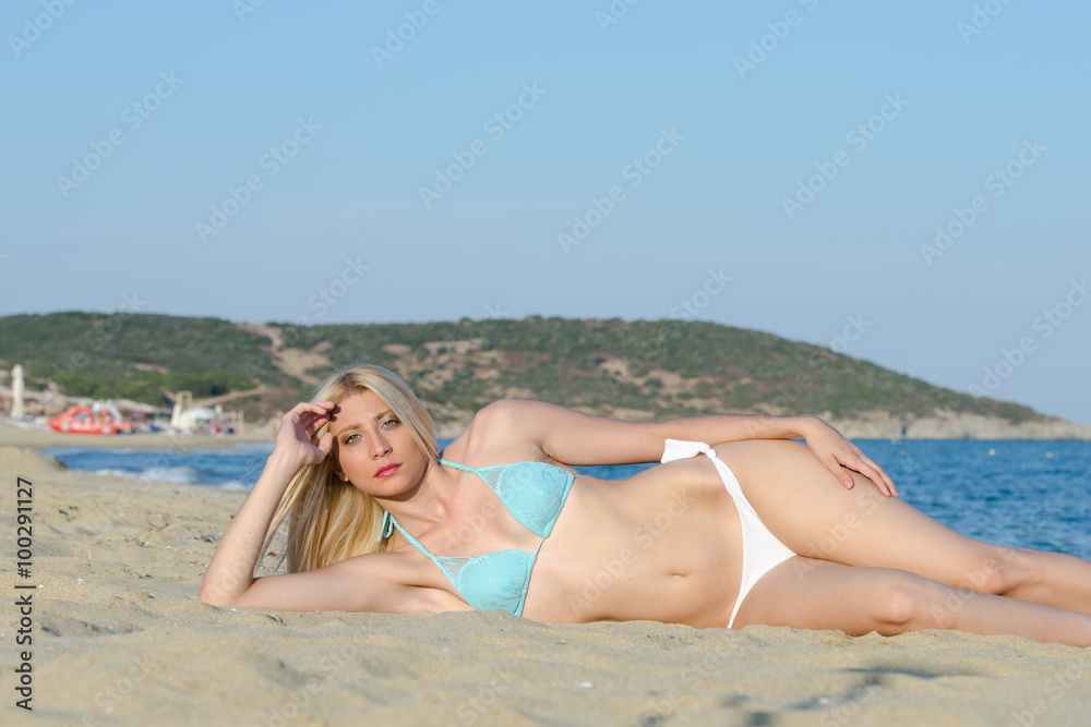 Blonde woman with amazing slim body wear bikini lying on the sand