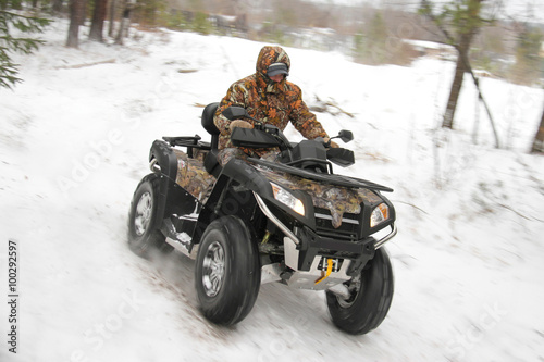 man driving a quad bike in the winter forest