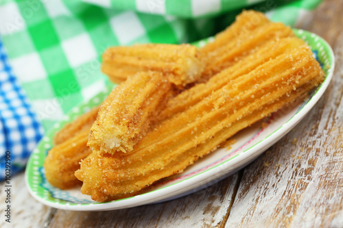 Spanish churros sprinkled with sugar and cinnamon on plate
