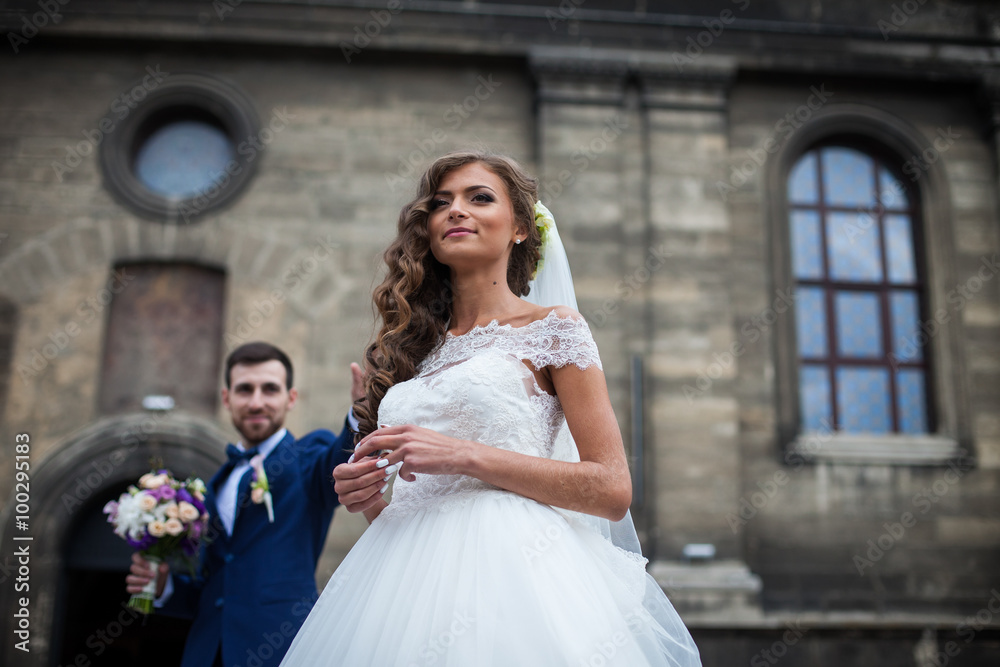 Happy couple of newlyweds valentynes posing in front of old baroque church bride closeup Happy couple of newlyweds valentynes posing in front of old baroque church bride closeup