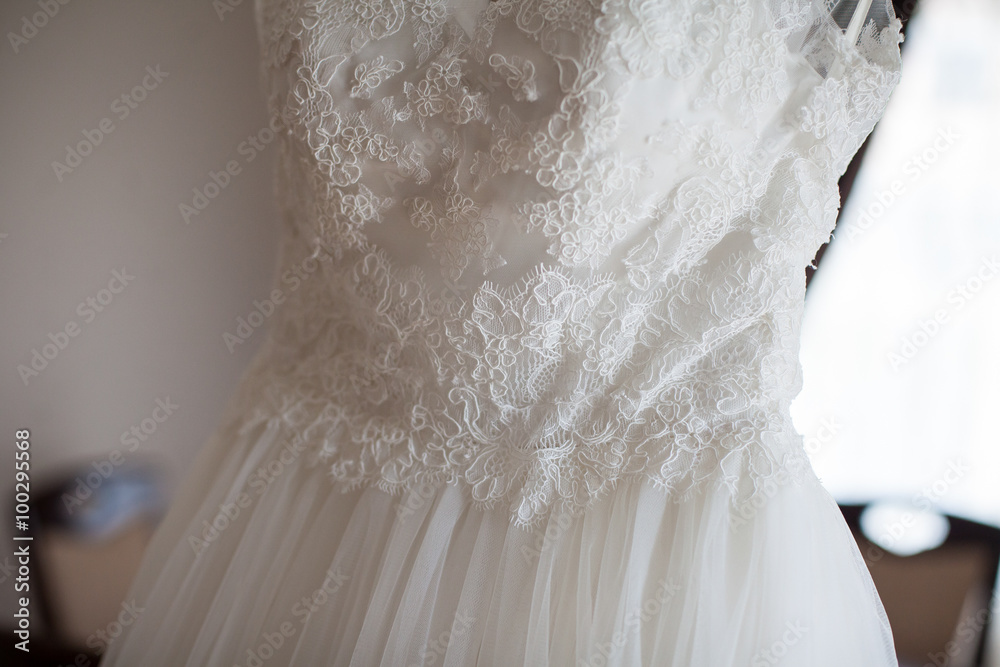 Elegant vintage white dress on a hanger in luxury hotel room closeup