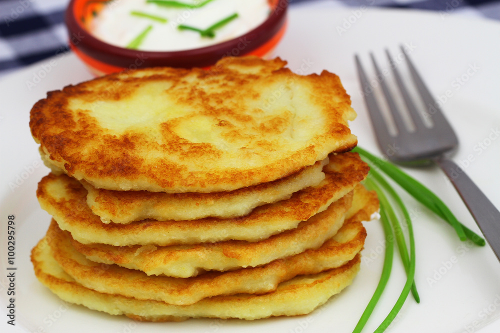 Stack of golden potato fritters on white plate
