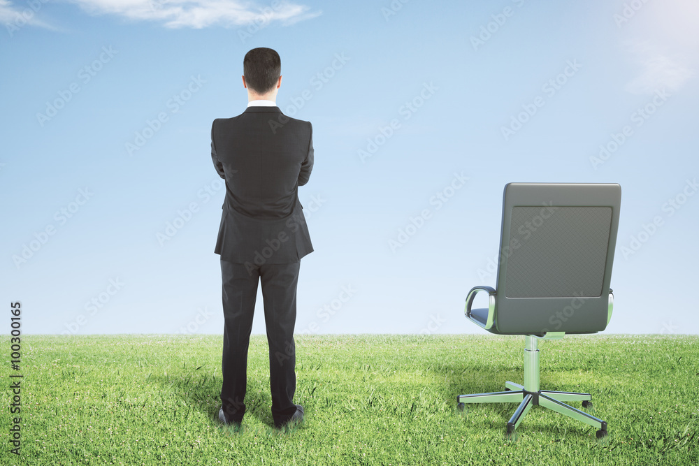 Businessman standing on a green grass and looks away Businessman standing on a green grass and looks away