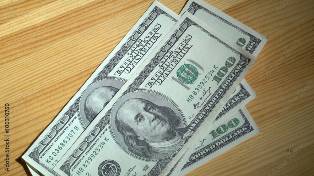 Counting 100 dollar bills on a wooden background Counting 100 dollar bills on a wooden background