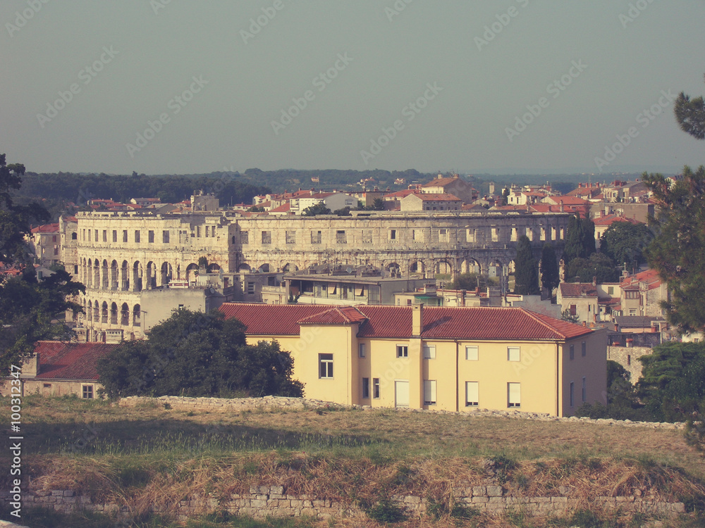 Panoramic view on the Croatian town of Pula in Istria, and its Roman Arena, on a sunny afternoon. Image filtered in faded, retro style with soft focus; nostalgic, vintage concept of travel.