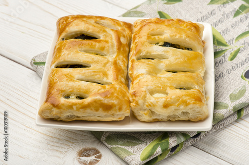 Puff pastry with spinach and feta on the wooden background.