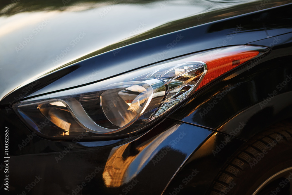 Close-up car headlight of powerful modern black car with glare.