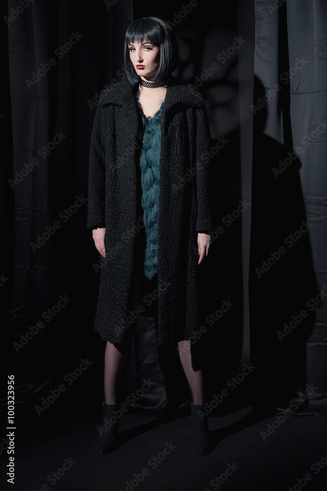Witch fashion woman wearing black coat. Standing in dark room. Witch fashion woman wearing black coat. Standing in dark room.
