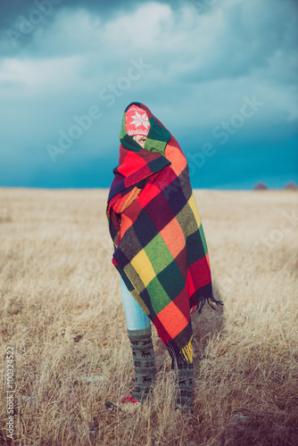 Happy free woman carefree in autumn or winter under a warm blanket enjoying the sun. Beautiful Caucasian girl outdoors.