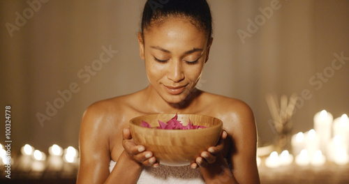 Young woman holding bowl with aromatic water and petals for spa photo