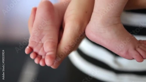 A close up shot of an young adult's hand holding two of a baby's feet. photo