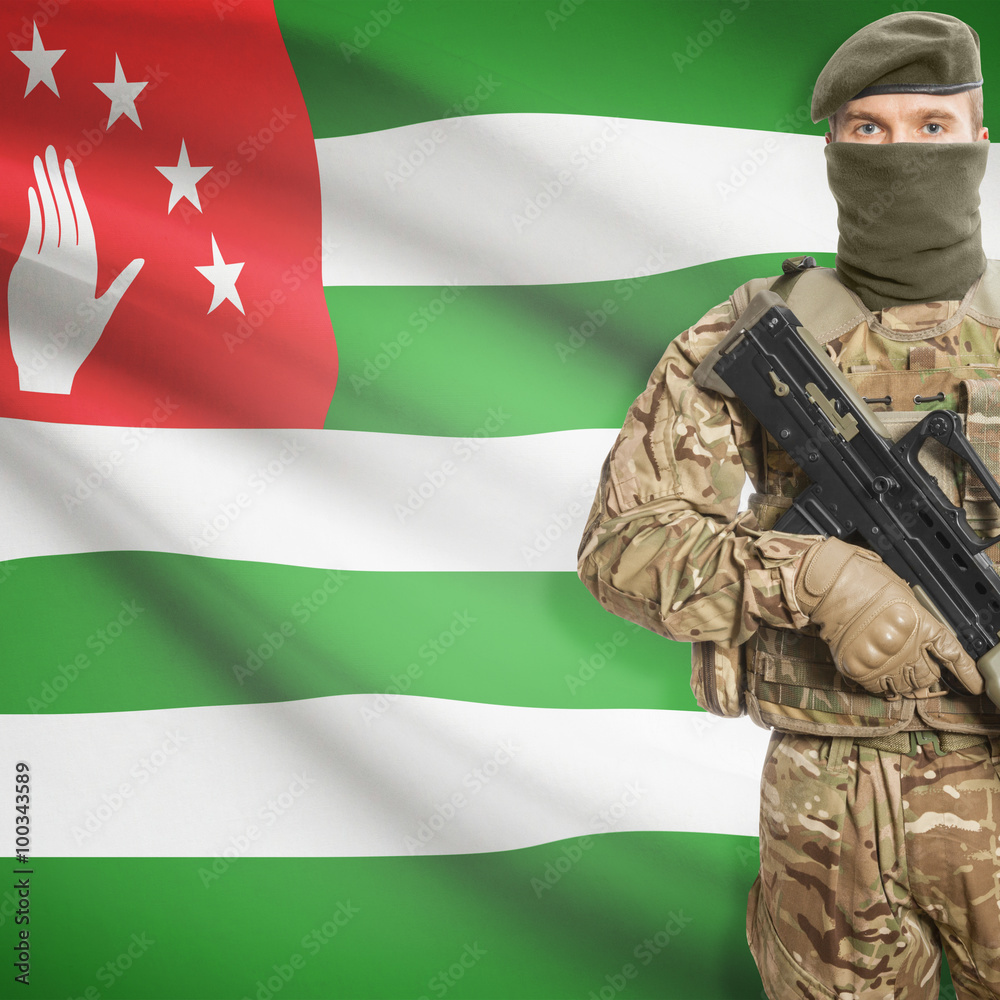 Fototapeta premium Soldier with machine gun and flag on background - Abkhazia