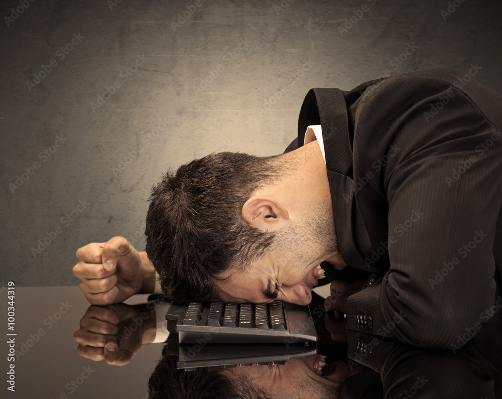 Obraz premium Frustrated businessman's head on keyboard