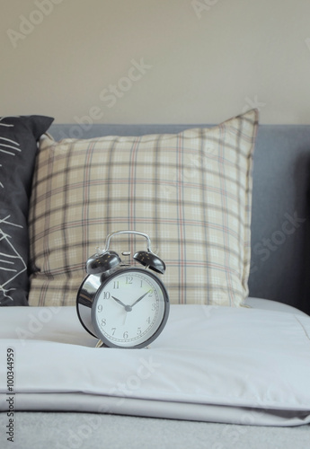alarm clock and graphic pattern pillows on bed