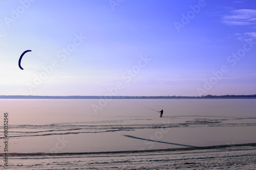 Narciarz ze spadochronem na zamarzniętym jeziorze.