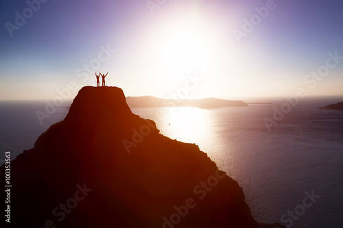 Happy couple on the top of the mountain over ocean celebrating life, success