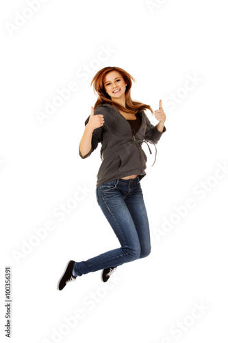 Teenage woman jumping showing thumbs up