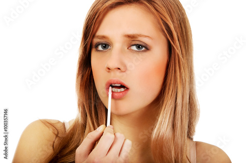 Teenage woman applying lip gloss