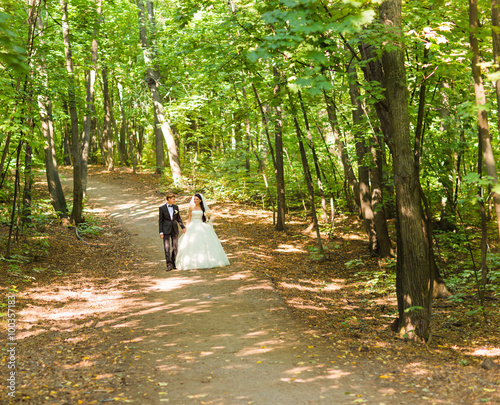 Bride and Groom at wedding Day walking Outdoors. Newlyweds in the park.